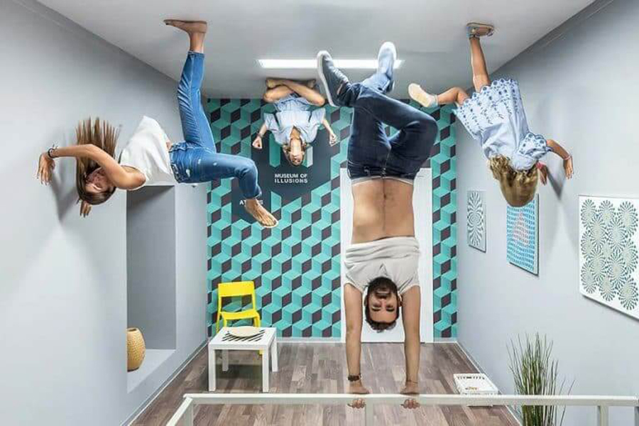 Group of people in a room in what seems they are hanging upside down inside the Museum of Illusions